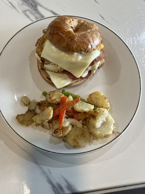 Pork roll egg and cheese on a French toast bagel with a side of home fries with onion and peppers