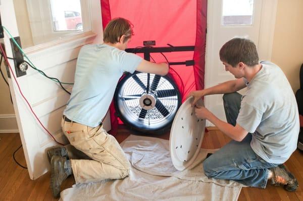 Setting up a blower door test during a Home Energy Audit to pinpoint energy efficiency problems in the home.