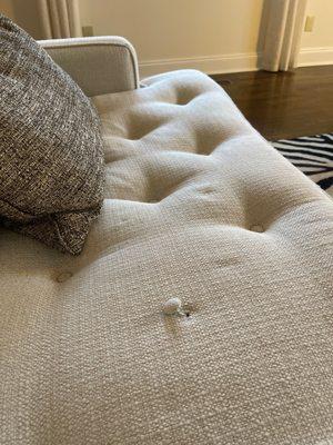 Sofa cushion showing tuft needing repair.