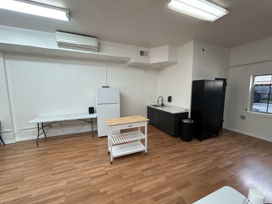 Cozy kitchenette area with a sink, refrigerator, and a mobile island, perfect for event catering setups.