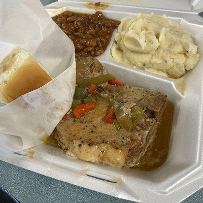 Smothered pork chops with baked beans and mashed potatoes.