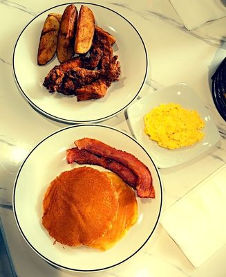 Pancakes bacon a side of scrambled eggs and cheese with chicken fingers fried hard and potatoes wedges