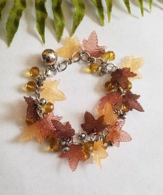 Shiny silver and gold beads bracelet flanked by breezy maple leaves. Get adorned!