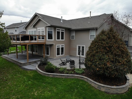 Raised patio under deck with garden block wall surrounding landscape