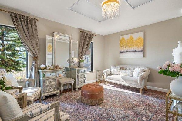 Rental suite with vanity, loveseat, armchair, and gorgeous chandelier. Get dressed in style in this  space!