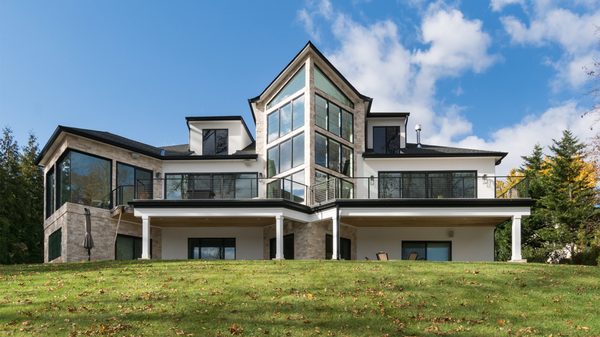 New modern home in New Jersey with magnificent waterfront facade. Floor to ceiling windows span three floors, illuminating interiors.