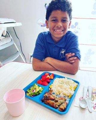 Noah enjoying chicken Parmesan wings salad and strawberries.