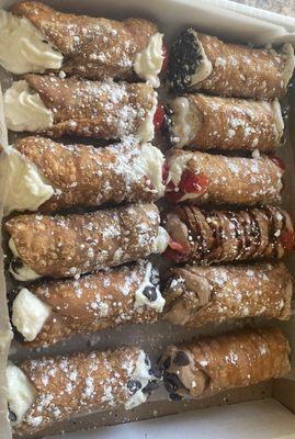 A Dozen cannolis ranging in flavors including strawberry, chocolate, espresso, and traditional