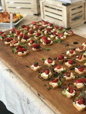 2 types of crostini at a brand launch party in an art studio. Strawberry,brie,onion jam & cherry tomato, mozzarella and basil balsamic glaze