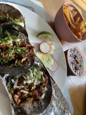 Salsa and chips along with al pastor and chorizo tacos.