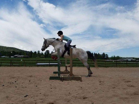 Our Trainer, Brittnee, working with a horse jumping.