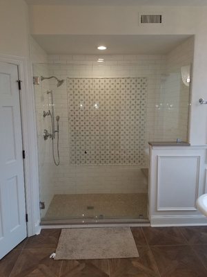 Hand-made subway tile shower with accent wall and frameless shower door.