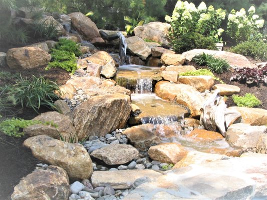 Pondless waterfall water feature flanked with landscaping