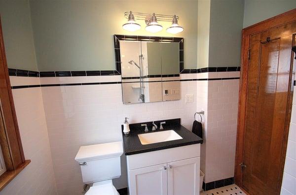 "After" photo: The medicine cabinet is now built in. The sink vanity is at a higher height. Art Deco light fixture