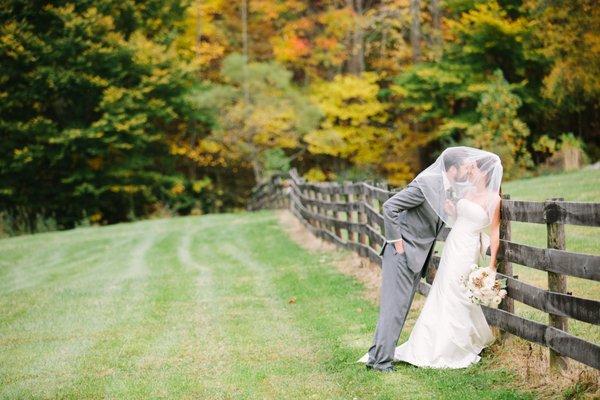 Bride and groom on the fence at their rustic barn wedding