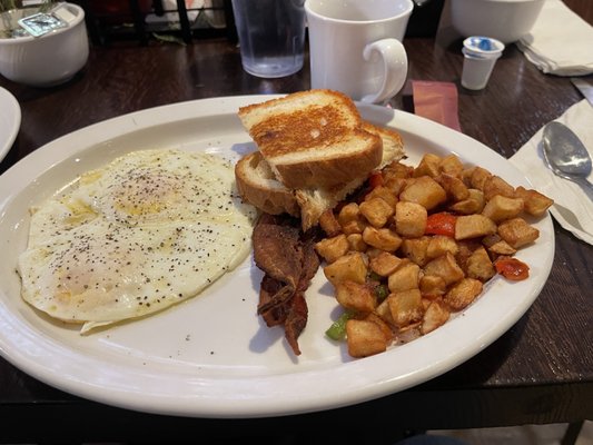 Two eggs, bacon, potatoes and toast breakfast