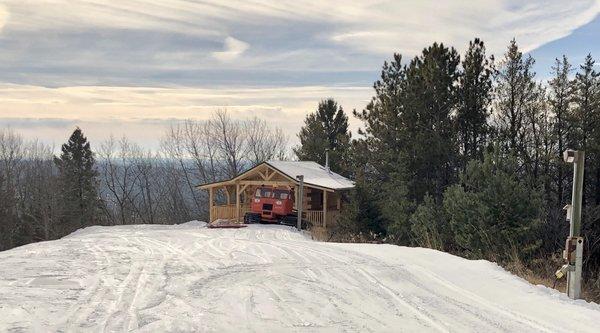 Groomer parked in front of cabin on top of the hill