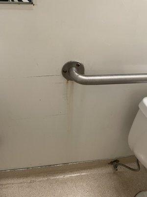 Rust stains behind the toilet.