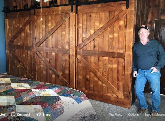 Full wall closet with sliding barn wood doors added to a farmhouse master bedroom.