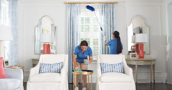 Maid Brigade team members cleaning a living room space.