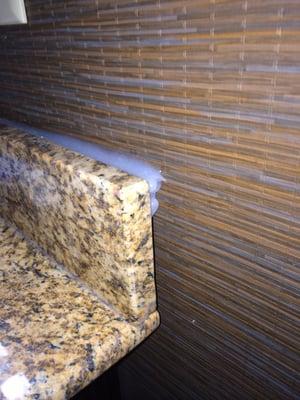 Bathroom counter top backsplash with about 3/4" gap where they tried to fill it in with caulk.