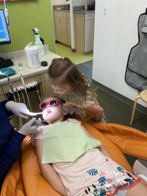 Cousin watching her cousin get teeth cleaned.