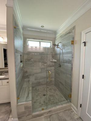 Frameless shower door with brass handle and hinges.