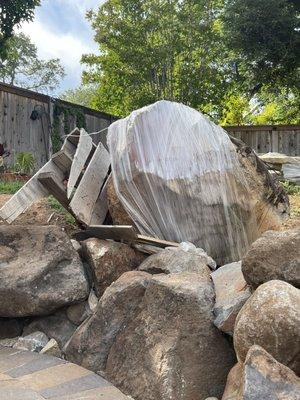 Boulder on broken pallet with nails exposed.