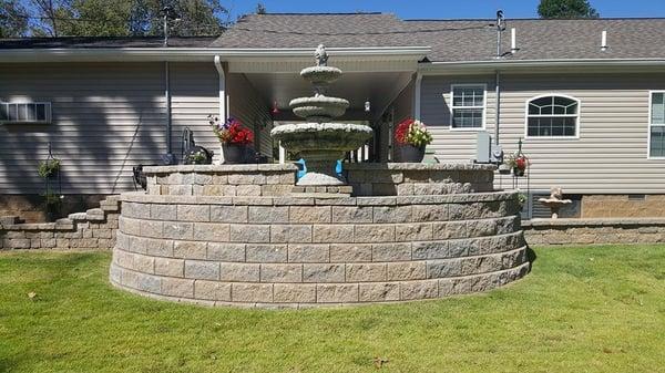 A raised paver patio, retaining wall with fountain installed at a lake house on Kentucky Lake, Paris, TN. by Lawnmasters Lawn and Landscape