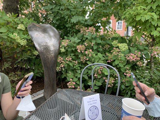 Corner outdoor table with a bronze sculpture of what looks like the back of a cobra's head