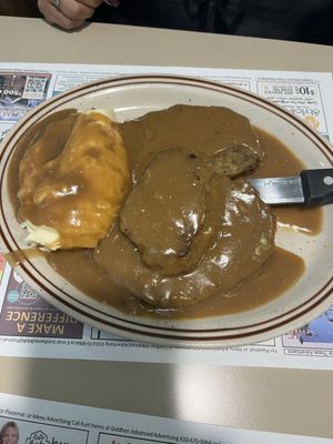 Mashed potatoes with steak and gravy.