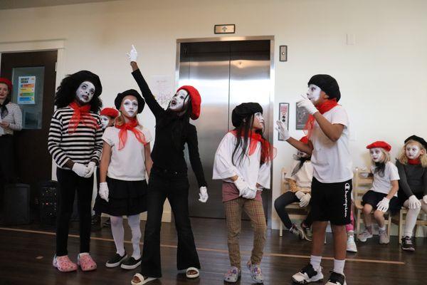 Student performance of their self-written scenes of life events. One child narrated while the others acted out the story in mime.