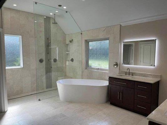 large walk in shower with "zero threshold". Also includes freestanding tub with ceiling tub filler.