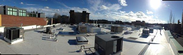 Nice panoramic photo of a commercial roof top with the sun in the back ground