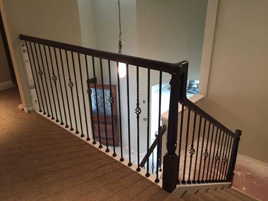 Over the post wood railing w/ iron balusters.