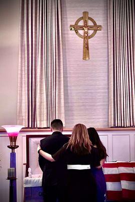 A mom supports her children as they say goodbye to their grandfather.