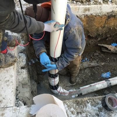 Picture demonstrates a technician and apprentice installing a tracer wire for future locating of sewer line lateral We just installed.