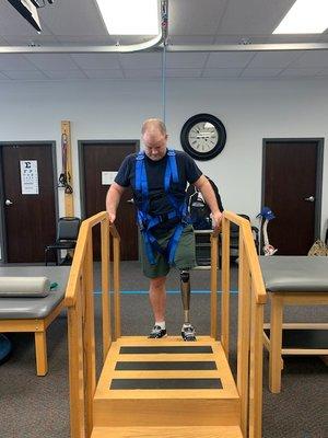 A patient attached to the Overhead Harness System, works on exercises to improve ambulation & gait.