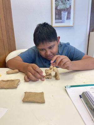 Child working on a 'triggerword' usong clay