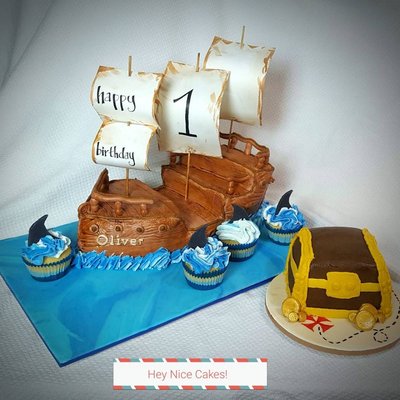 Pirate ship first birthday cake with shark fin cupcakes and treasure chest smash cake