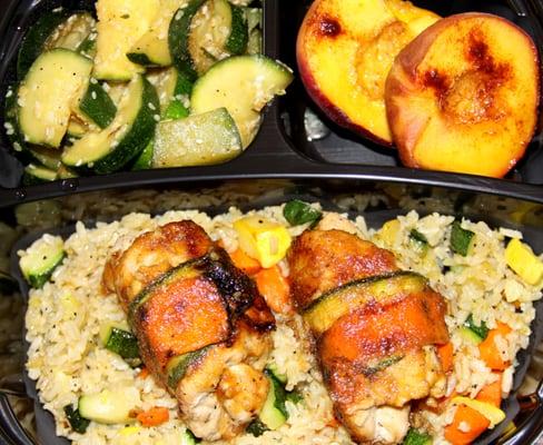 Grilled chicken wrapped with carrots and zucchini on a bed of vegetable rice served with sauteed zucchini and roasted fruit.