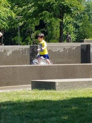 Children enjoy the water features on a hot summer day.