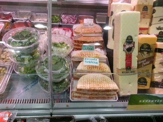 Display case with sandwiches salads and cheese