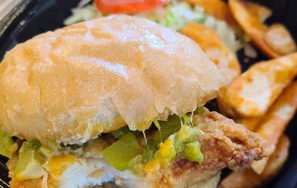 Lightly Breaded Grilled Chicken Breast topped with green chile, melted cheese on a toasted Bun