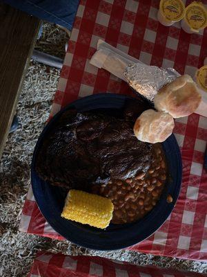 Steak, potato, corn, biscuits, and beans