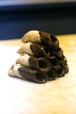 Half-chocolate dipped mini cannoli shells ready for filling.