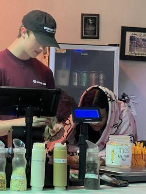 Staff at the register with a blanket wrapped around her while the tables are dirty and  no toilet paper in the bathroom.