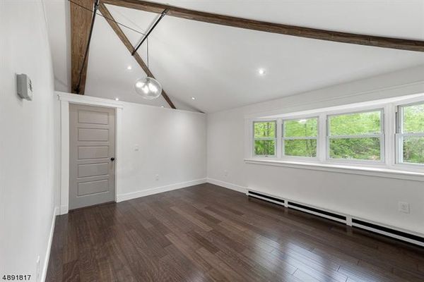 Master bedroom with walk in closet, vaulted ceiling, custom decorative beams and heater covers, and bay window