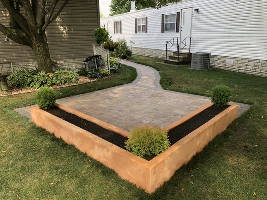 Paver walkway leading into a Belgian paver patio,accented with a stucco flower planter feature.