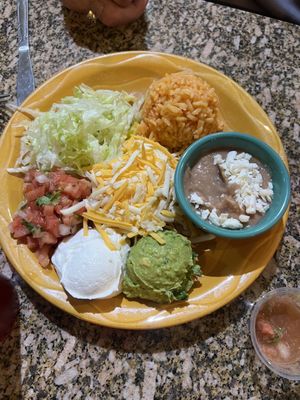 Side of rice, refried beans, shredded lettuce, sour cream, salsa, cheese